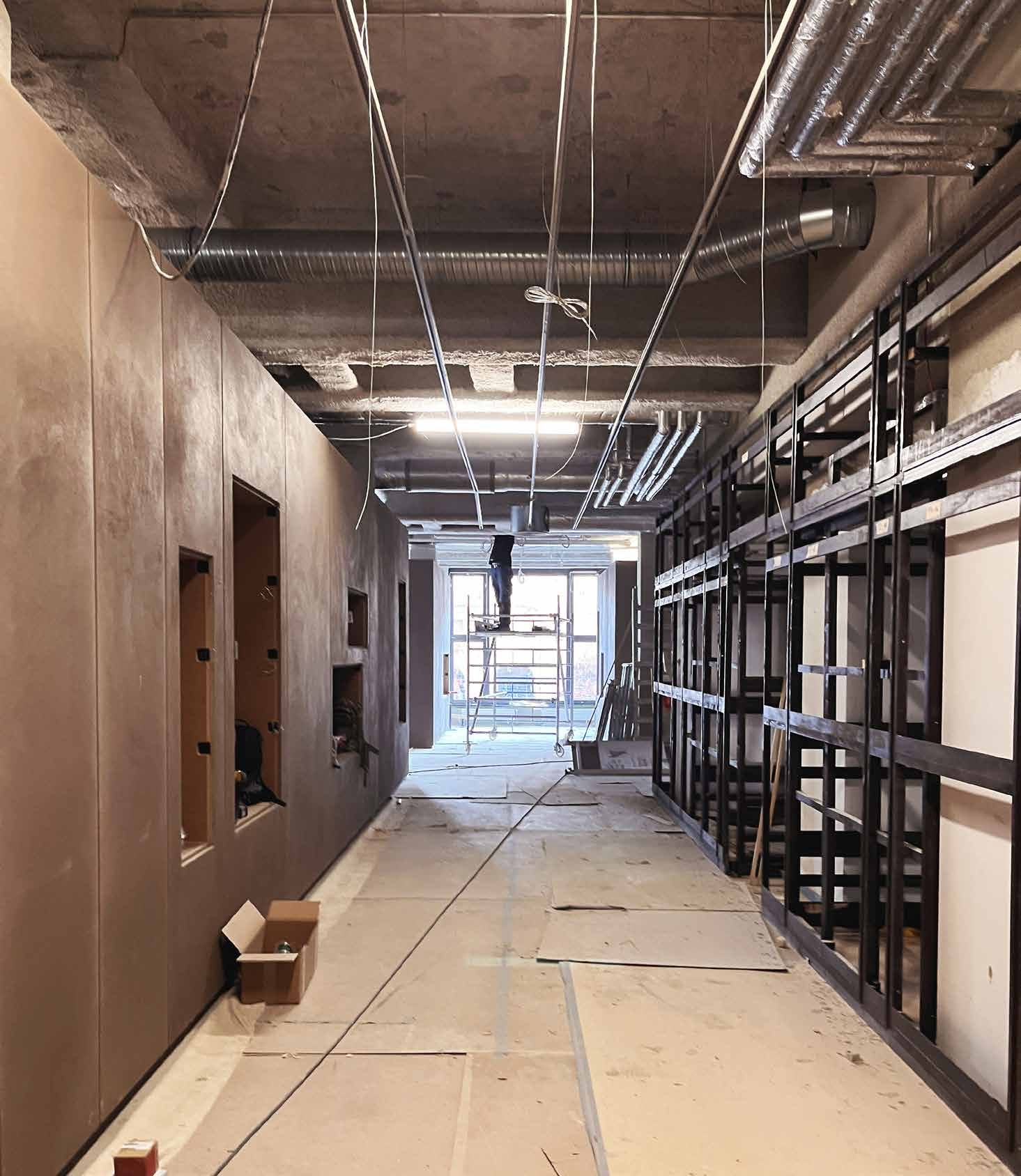 The Papenbreer store under construction: a long aisle with drywall partitions, an open ceiling with ventilation ducts and black steel shelving