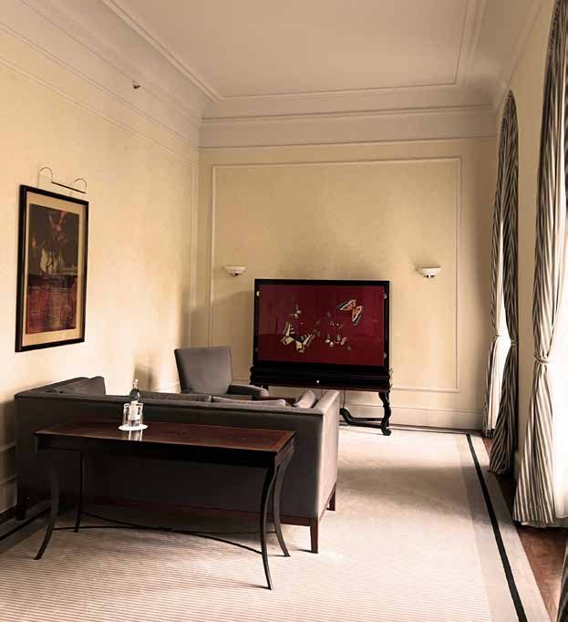 The living room of the bridal suite before the refurbishment: beige walls, a desk, a dark sofa and a red lacquered cabinet