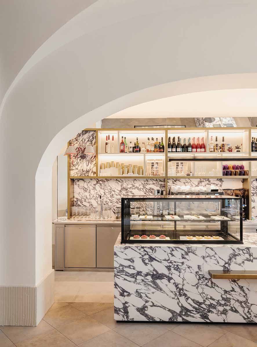 The Patisserie Amalia today: a counter with a glass display case and marble cladding beneath a white vaulted arch, with illuminated shelves behind