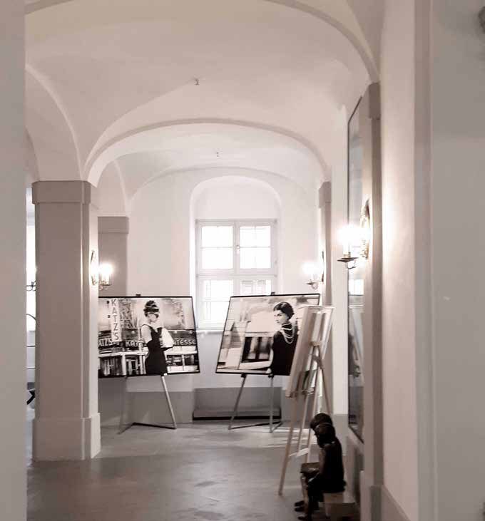 The patisserie space before the refurbishment: a white-plastered vaulted passage with piers and a photo exhibition on easels