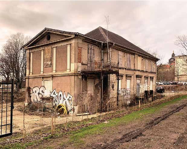 Vorher: dieselbe Seite als Ruine — verfallene Veranda, Graffiti und lehmiger Weg vor dem leerstehenden Haus